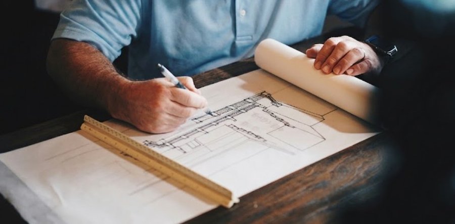 Hand zeichnet einen technischen Bauplan mit Bleistift und Lineal